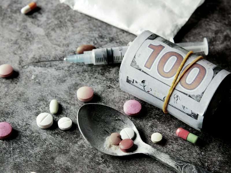 a close up shot of a roll of money and various drugs
